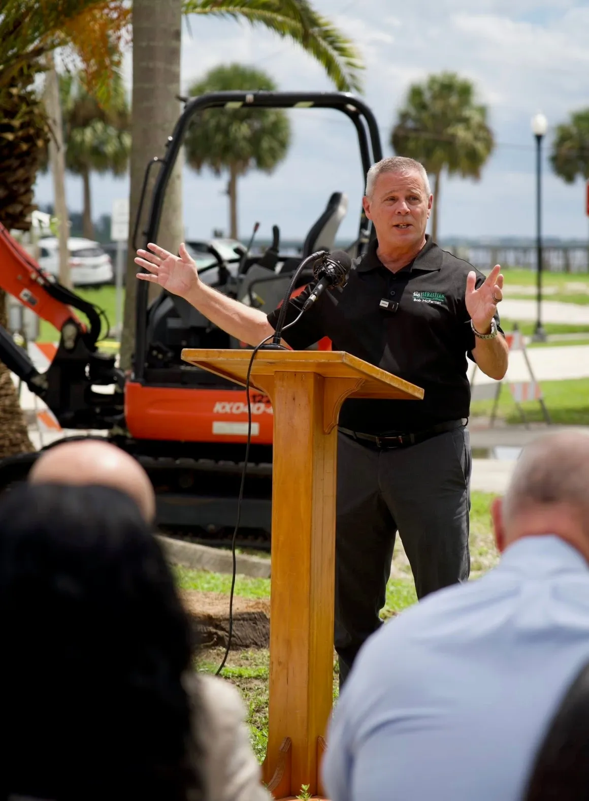 Bob McPartlan speaking at a podium during a groundbreaking ceremony in Sebastian, Florida