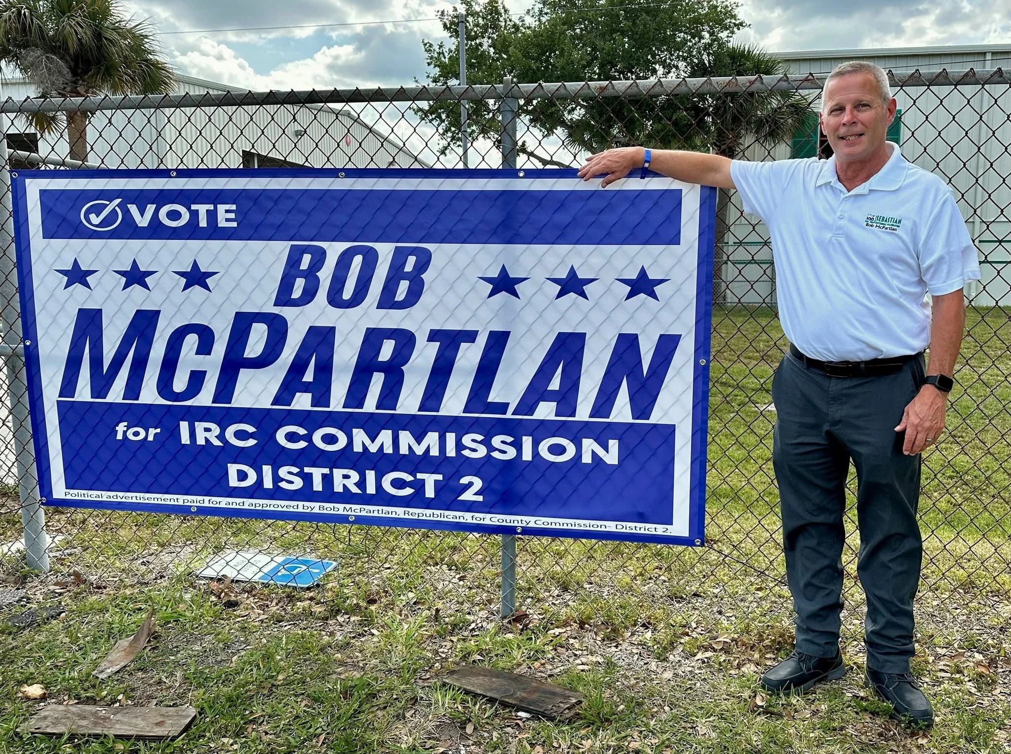 Bob McPartlan standing beside his campaign yard sign: Vote Bob McPartlan for IRC Commission District 2